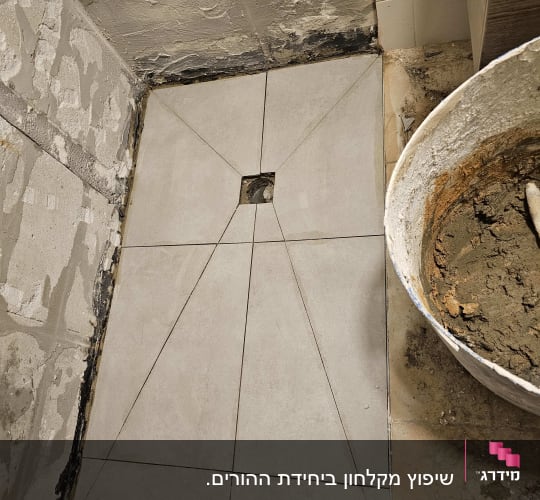 ריצוף חדש בתהליך שיפוץ עם דלי מלט